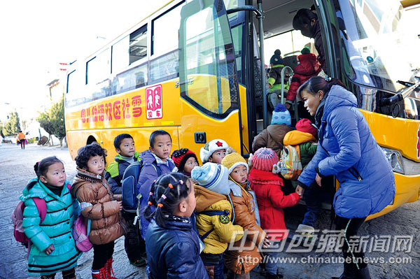 西藏2013年1月1日起校車擁有優先通行權/ 幼兒園老師正在組織學生上校車。