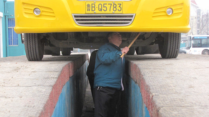 青島開學前溫馨校車安全大檢查/ 檢車人員正在對校車底部進行檢查