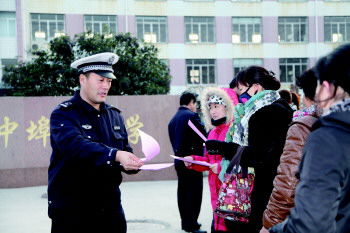 交警在學(xué)校門口向家長發(fā)放校車安全宣傳單(資料片)。